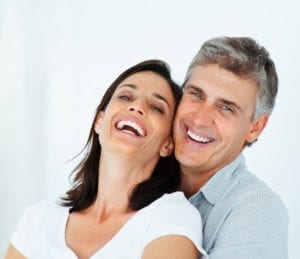 A couple smiling and showing white teeth after visiting a metal-free dentist.